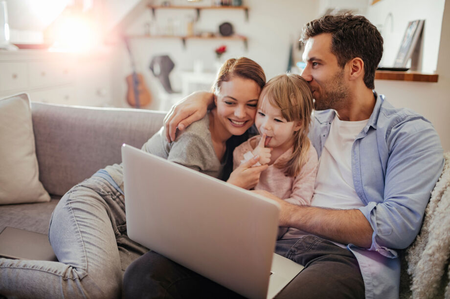 Family having a cuddle on the sofa in front of a laptop